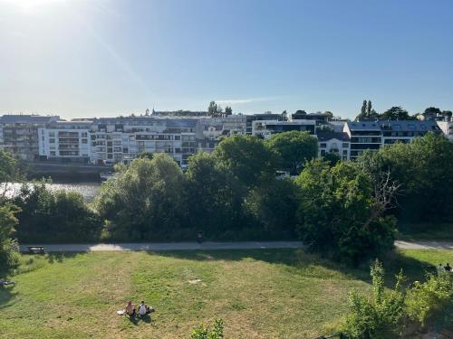un groupe de personnes assises dans un champ herbeux avec des bâtiments dans l'établissement Sur Erdre chambre et salle de bain, à Nantes