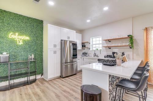 a kitchen with white cabinets and a green wall at Backyard Movie Nights! Galveston Beach Retreat in Galveston