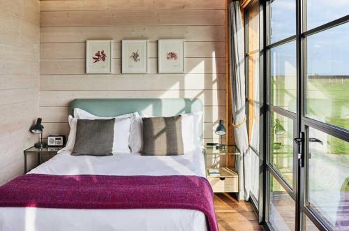 a bedroom with a bed and a large window at Cabu by the sea in Dymchurch