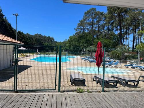 une clôture avec deux bancs et une piscine dans l'établissement Mobil-home, à Bias