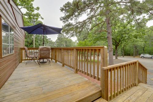 a wooden deck with a table and an umbrella at Greers Ferry Lake Escape Cabin with Pool Access in Higden