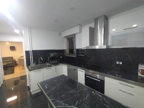 une cuisine avec des comptoirs en marbre noir dans une pièce dans l'établissement 4 min walk to metro, 3 bedrooms &Salon, La Défense, à Courbevoie