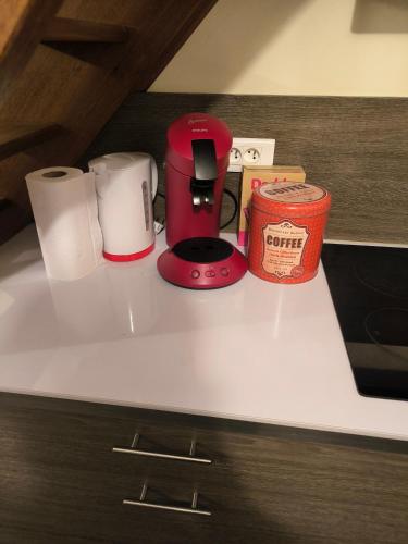 - une cafetière rouge et des serviettes en papier sur un comptoir dans l'établissement Appartement F2 centre ville, à Auxerre