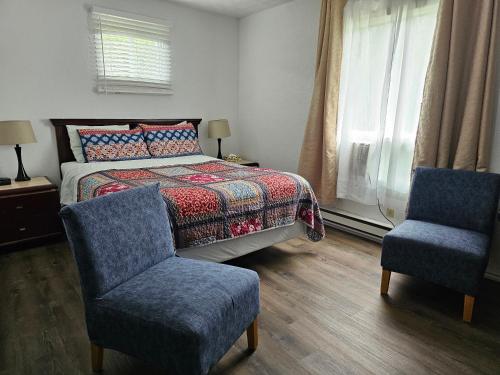 a bedroom with a bed and two chairs at Motel de l'Outlet in Magog-Orford