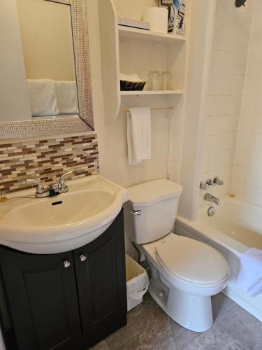 a bathroom with a sink and a toilet and a tub at Motel de l'Outlet in Magog-Orford
