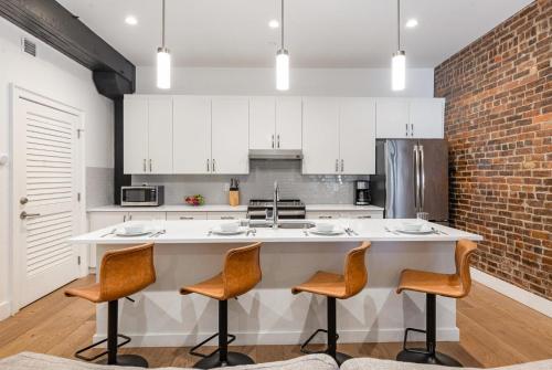 a kitchen with a large white counter with chairs at The Saddlery - Key Note - Walk to Broadway in Nashville