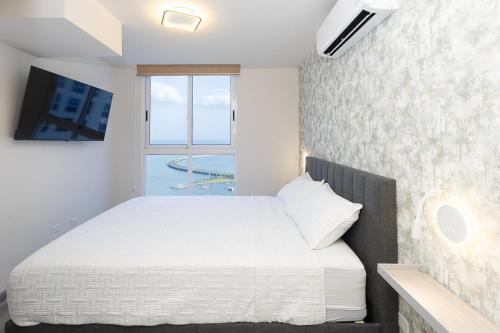 a bedroom with a white bed and a window at The Sands Apartments By Acomodo in Panama City