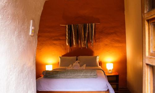 a bedroom with a bed with two lights on the wall at Loki Cusco in Cusco