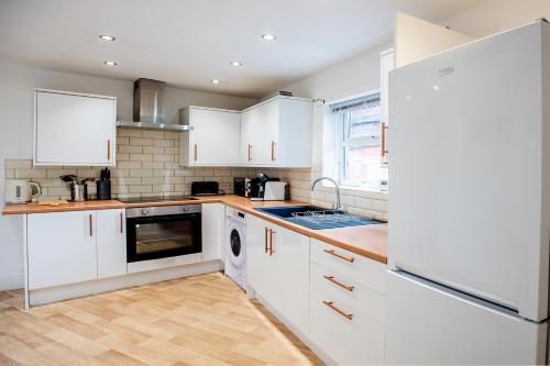a kitchen with white cabinets and a refrigerator at Newly Furnished Cosy 3 bed 20mins from City Center in Manchester