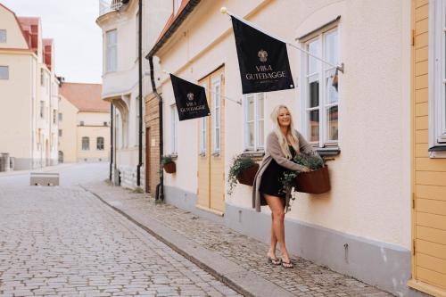 a woman standing in front of a building with flags at Villa Gutebagge Hotell in Visby