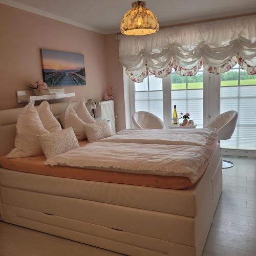 a large bed in a bedroom with a chandelier at Strandmuschel in Aventoft