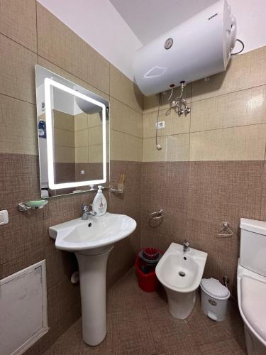 a bathroom with a sink and a toilet and a mirror at Xh&S Apartament in Durrës