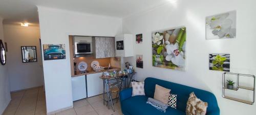 un salon avec un canapé bleu et une cuisine dans l'établissement Nice Ouest, studio apartment near the beach, à Nice