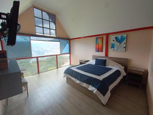 a bedroom with a large bed and large windows at HCR Hotel y Centro de Convenciones Chinauta Real in Fusagasuga