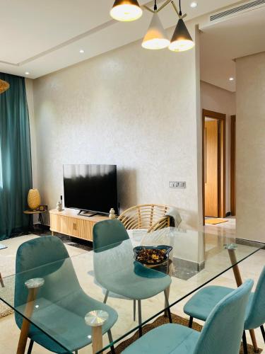 a living room with blue chairs and a television at Elegant & Cozy Beach Apartment in Mohammedia