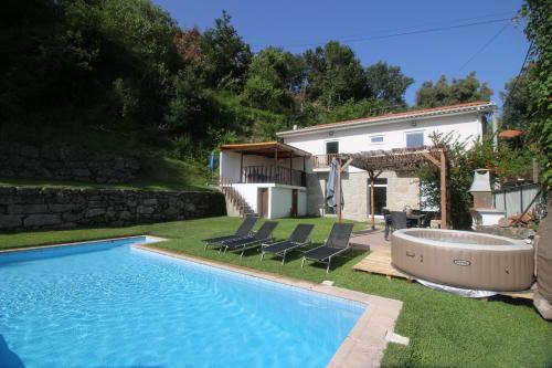 a swimming pool in a yard with chairs and a house at Casa da Pontelha by Gerês Casas in Terras de Bouro