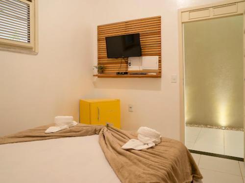 a bedroom with a bed and a tv on the wall at Suítes Pe na Areia in Jericoacoara