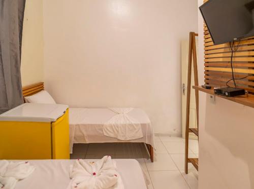 a small room with two beds and a television at Suítes Pe na Areia in Jericoacoara