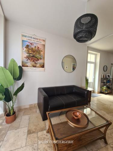 a living room with a leather couch and a coffee table at Dors Fée Duplex avec Toit-Terrasse et Salle de Jeux - Centre Bourg à 4 min du Puy duFou in Les Épesses