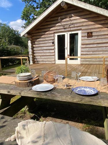 a wooden table with plates and glasses on it at Knus boomstamhuisje op de Schatberg - nabij Toverland in Sevenum