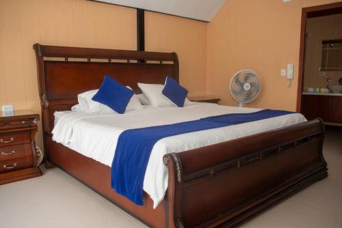 a bedroom with a large bed with blue and white pillows at HCR Hotel y Centro de Convenciones Chinauta Real in Fusagasuga