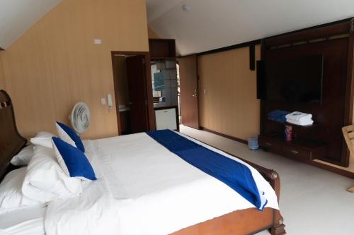a bedroom with a large bed with blue pillows at HCR Hotel y Centro de Convenciones Chinauta Real in Fusagasuga