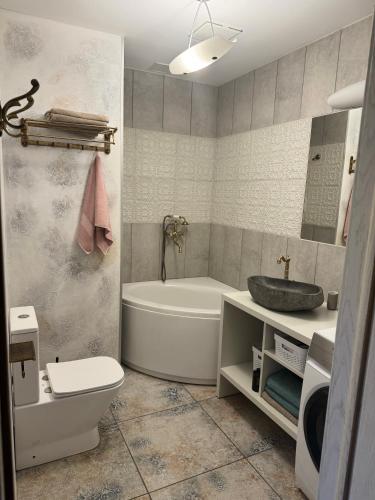 a bathroom with a tub and a toilet and a sink at Cozy Apartment in Vilnius Paupys in Vilnius
