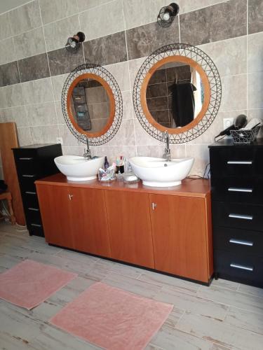 une salle de bain avec deux lavabos et deux miroirs dans l'établissement le verger 16km du circuit du Mans 8 min de l'autoroute, à Parigné-lʼÉvêque