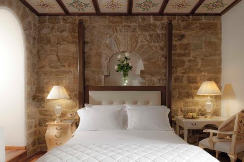 a bedroom with a white bed and a stone wall at Golden Tower Hotel & Spa in Florence
