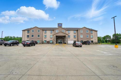a large building with cars parked in a parking lot at Cobblestone Hotel & Suites - Russells Point at Indian Lake in Russells Point