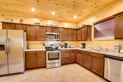 eine Küche mit Holzschränken und Geräten aus Edelstahl in der Unterkunft Bears Den by Venture Smoky Mountains in Gatlinburg