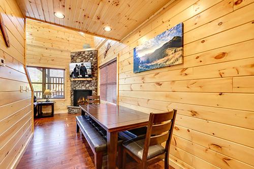 ein Esszimmer mit einem Holztisch und einem Kamin in der Unterkunft Bears Den by Venture Smoky Mountains in Gatlinburg