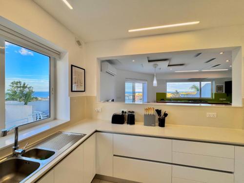 a kitchen with white cabinets and a sink and a window at St Julians Hillside villa with Pool in Is-Swieqi