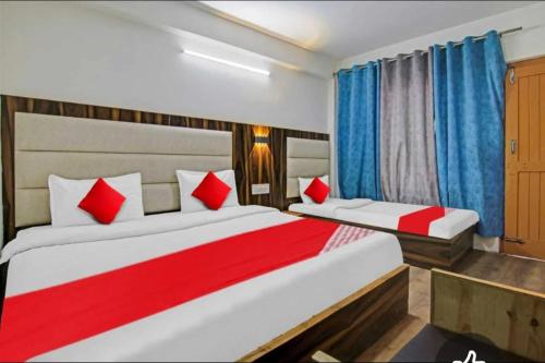 Dos camas en un dormitorio con cortinas rojas y azules. en Hotel Alfa Manali, en Manali