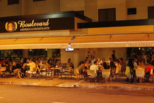a group of people sitting at tables outside a restaurant at Boulevard Suíte Hotel by WAM Experience in Caldas Novas