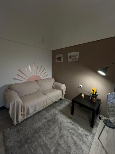 een woonkamer met een witte bank en een tafel bij La petite maison Soleil in Biella