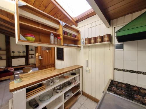 Una cocina con paredes blancas y encimeras y estantes de madera. en Cabaña El Camino, en San Martín de los Andes