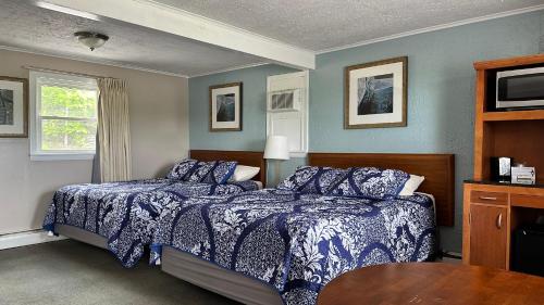 a bedroom with two beds and a table and a tv at Mount Blue Motel in Farmington