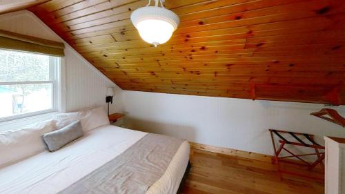 a bedroom with a white bed and a wooden ceiling at Elmhirst's Resort in Keene