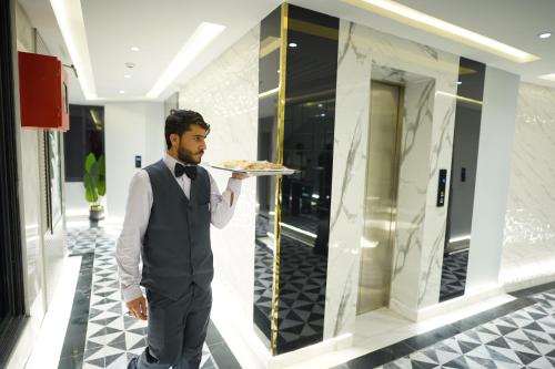 a man in a suit holding a plate of food at The Khushi Hotel And Resorts in Murree