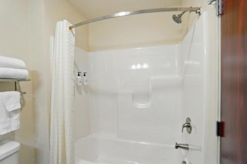 a bathroom with a shower with a shower curtain at Cobblestone Hotel & Suites - Russells Point at Indian Lake in Russells Point