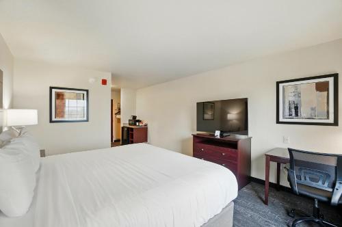 a hotel room with a bed and a flat screen tv at Cobblestone Hotel & Suites - Russells Point at Indian Lake in Russells Point