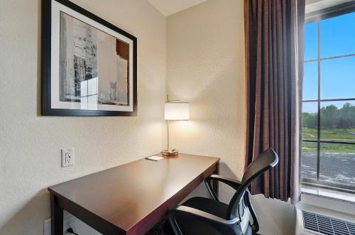 a desk with a lamp and a chair in a hotel room at Cobblestone Hotel & Suites - Russells Point at Indian Lake in Russells Point