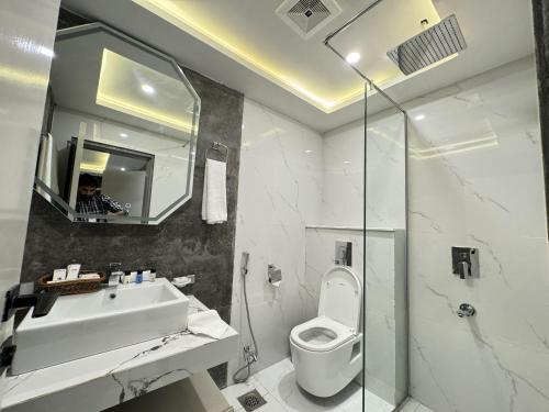 a bathroom with a sink and a toilet and a mirror at The Khushi Hotel And Resorts in Murree