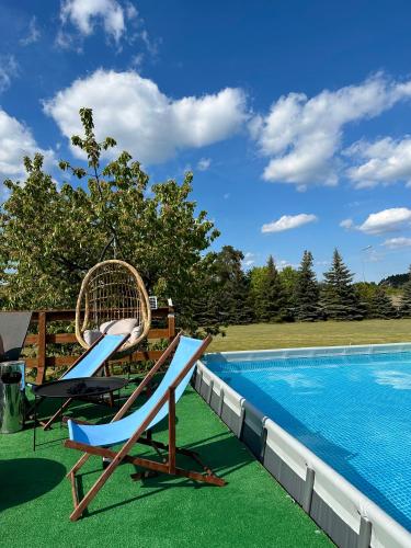 a pair of chairs sitting next to a swimming pool at Holiday - domki letniskowe in Charzykowy