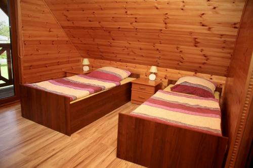 ハジコビにあるHoliday - domki letniskoweの木製の壁の部屋にベッドが2つある