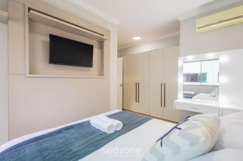 a bedroom with a bed with a tv on the wall at Apto 2Q - Churrasq. Garagem Perto da Praia LTL0301 in Meia Praia