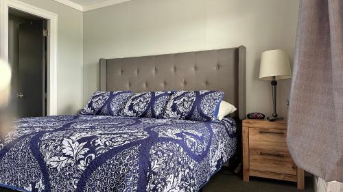 a bedroom with a bed with a blue and white comforter at Mount Blue Motel in Farmington