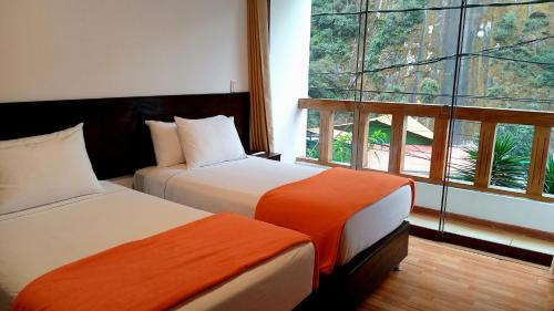 two beds in a room with a large window at El Quetzal MachuPicchu in Machu Picchu