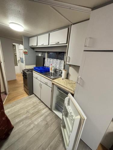 a small kitchen with white cabinets and a refrigerator at Domek wakacyjny 